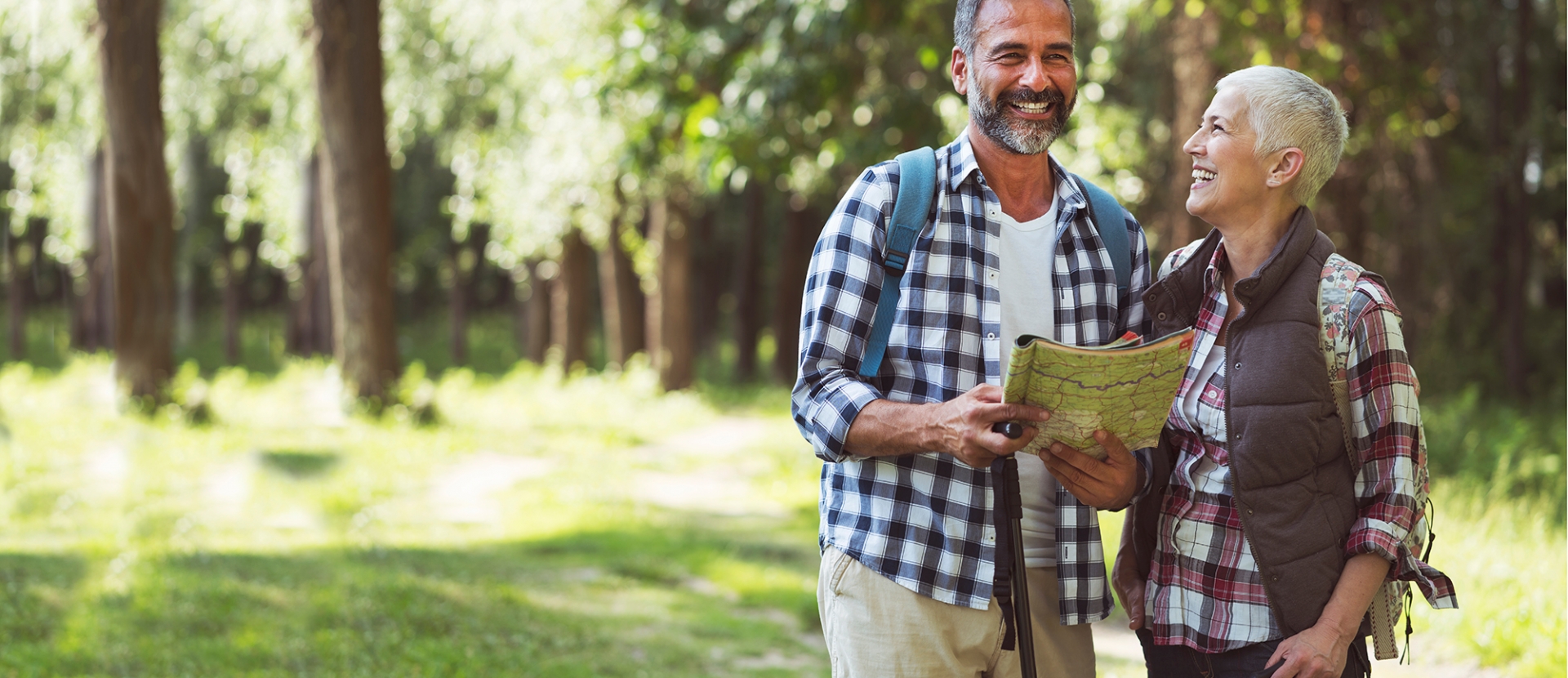 Elderly couple smiling while holding a map in the outdoors