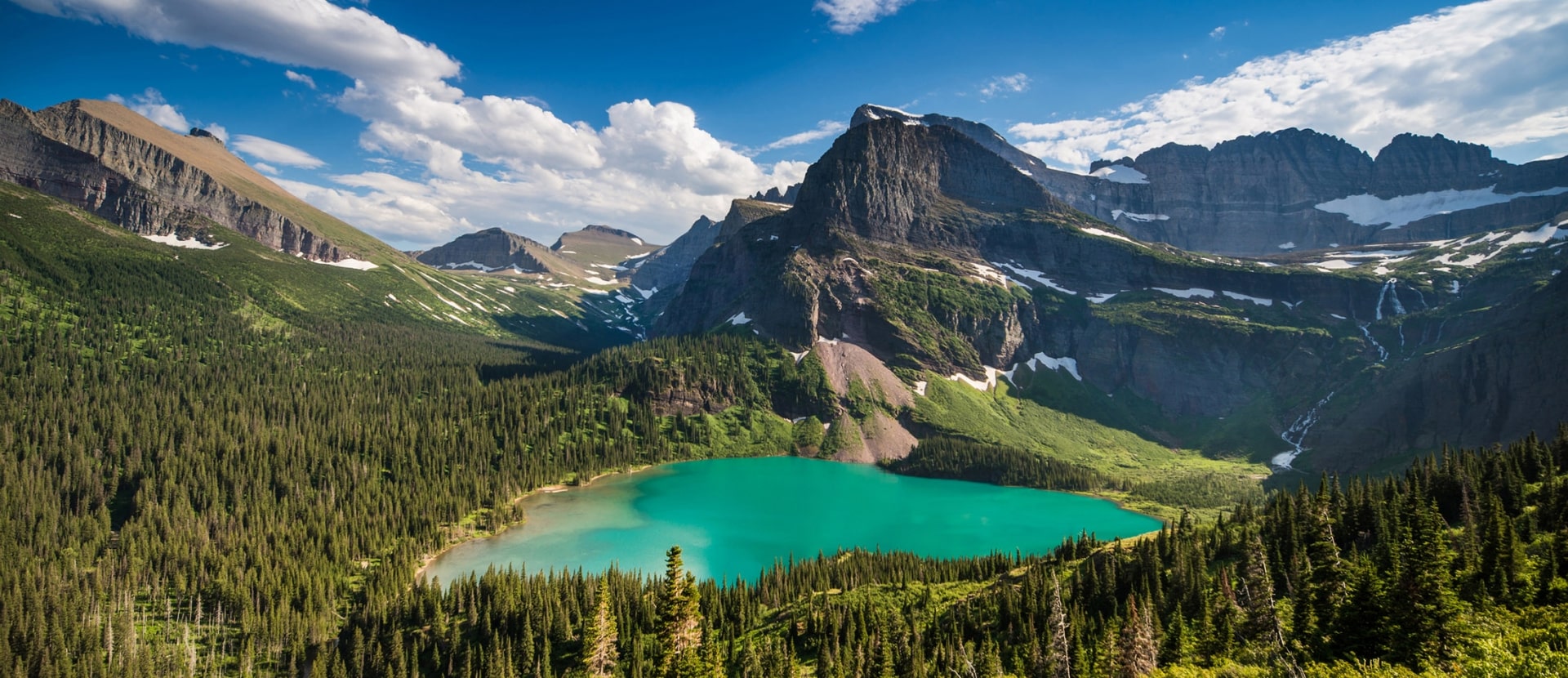 Scenic view of a lush mountain valley and lake at Glacier National Park